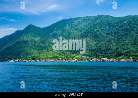 Montenegro, Beautiful green tree and forest covered mountains with coastal towns and houses alongside shore of kotor bay seen from perast Stock Photo