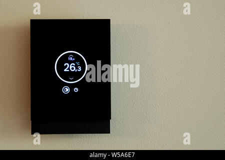Smart screen of the modern digital thermostat climate control isolated on the wall.- Image Stock Photo