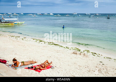 Young Women Sunbathing On Alona Beach, Bohol, The Philippines Stock Photo