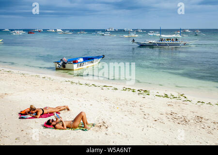 Young Women Sunbathing On Alona Beach, Bohol, The Philippines Stock Photo