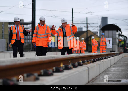 Prime Minister Boris Johnson (right) walks with CEO of Transport for the North Barry White (left) and Britain's Northern Powerhouse Minister Jake Berry (centre) as he leaves the site of an under-construction tramline in Stretford, greater Manchester, before giving a speech on domestic priorities. Stock Photo