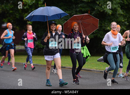 Women takes part in a run whilst holding umbrellas in Battersea Park, London. Stock Photo