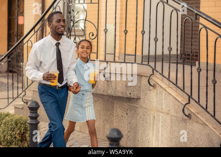 Proud little female walking with her father Stock Photo