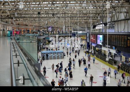 London, United Kingdom - July 22, 2019: Waterloo train station on weekday morning showing motion blurred commuters and balcony area Stock Photo