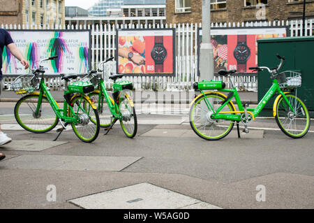 Electric bikes Lime-E parked on pavement in London Stock Photo