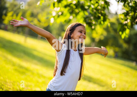 Happy little girl is enjoying nature in park. Stock Photo