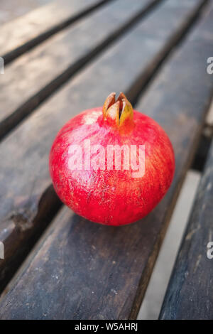 One red ripe pomegranate on a wooden table close-up. Whole pomegranate fruit Stock Photo