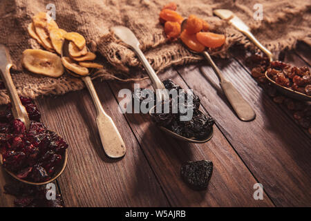 Dried fruits arranged on a spoon, fabric and an old table. Composition in the old style Stock Photo