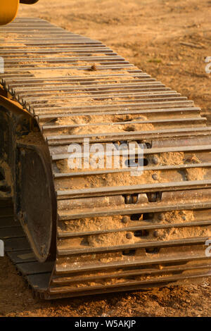 macro of the continuous tracks of a big bulldozer on a construction site with yellow sandy soil, dirty tractor tracks Stock Photo