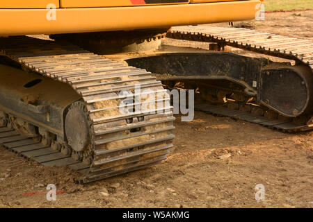 tracked wheel of a excavator bulldozer on soil, macro of the continuous tracks of a big bulldozer on a construction site with yellow sandy soil Stock Photo