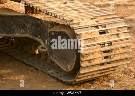 close up of tracked wheel, macro of the continuous tracks of a big bulldozer on a construction site with yellow sandy soil Stock Photo