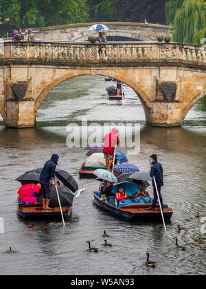 Punting in the Rain Cambridge  Ducks and geese follow punts full of tourists sheltering under umbrellas during heavy rain in Cambridge UK