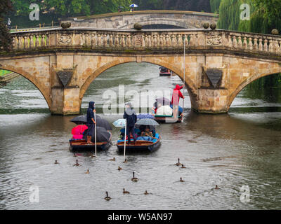 Punting in the Rain Cambridge  Ducks and geese follow punts full of tourists sheltering under umbrellas during heavy rain in Cambridge UK
