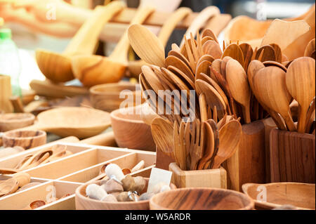 Wooden spoons, forks and other kitchen tools on a market stall. Stock Photo