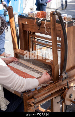 Close up hands of woman weaving color pattern on traditional hand-weaving wooden loom. Stock Photo