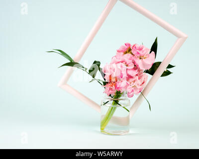 White landscape frame mockup with flowers in styled vase near blue wall. Empty frame mock up for presentation design. Template framing for modern art Stock Photo