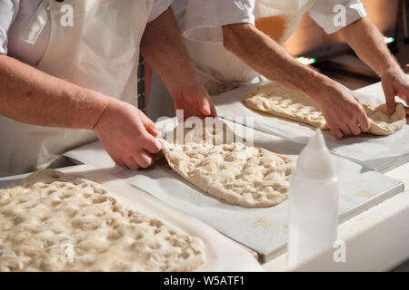 Baker is preparing a focaccia dough on a countertop. Stock Photo