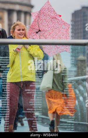 London, UK. 27th July, 2019. The hot weather is over and summer showess have replaced it on the Millennium Bridge. Credit: Guy Bell/Alamy Live News Stock Photo
