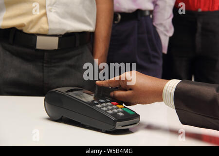 Shop assistant swiping credit card through machine Stock Photo