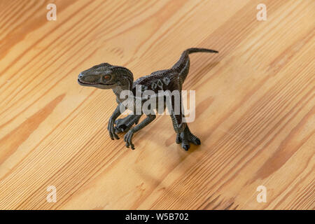 Children's toy ancient predator dinosaur on a wooden table in a room flooded with sunlight. Toy tyrannosaur from plastic. Ancient predatory reptile fr Stock Photo