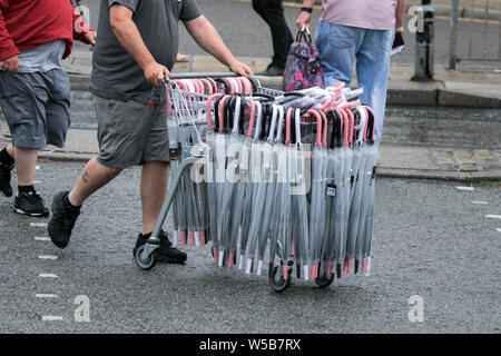 An umbrella salesman sells brollies from his portable trading stall in Liverpool Merseyside UK Stock Photo