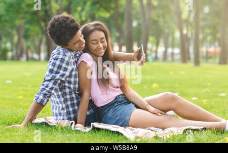 Romantic teenagers taking selfie on a date in park Stock Photo