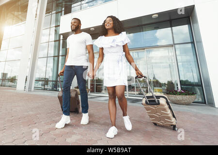 Happy black couple walking in front of airport terminal building Stock Photo