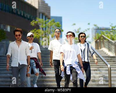 a group of five young asian adults hanging out together walking on street Stock Photo