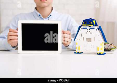 Boy holding tablet with blank screen and robot nearby Stock Photo