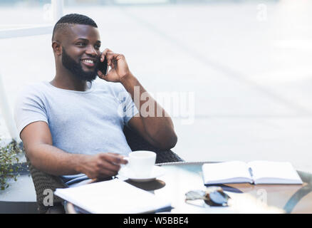 Young african guy relaxing during lunch time, drinking coffee Stock Photo