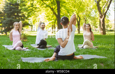 Group of people practicing yoga, sitting in Cow Face exercise Stock Photo