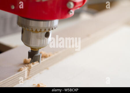 Close-up of the head of the drilling machine with nozzle in the furniture workshop, selective focus Stock Photo