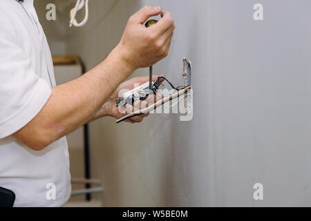 Work on installing electrical outlets with electrical wires and connector installed in plasterboard drywall Stock Photo
