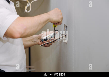 Hands professional during mounting of electrical outlets connector installed in plasterboard drywall in apartment is under construction Stock Photo