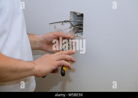 Construction in closeup of electricians hand installing outlet on wall with using professional tools. Stock Photo