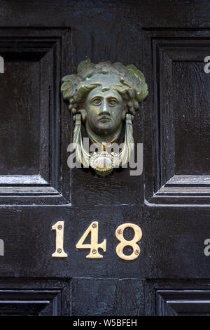 House number 148 on a black wooden front door with a door knocker in the shape of a female head Stock Photo