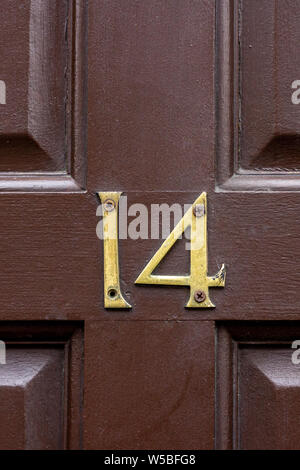 House number 14 on an old brown wooden front door Stock Photo