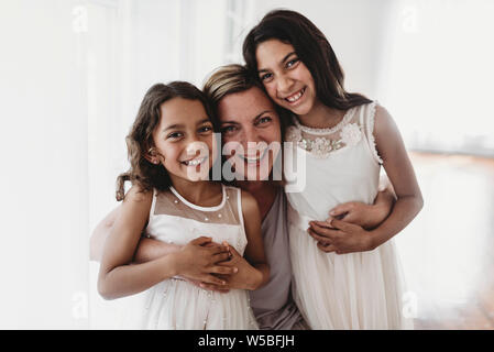 Portrait of mother and two daughters in natural light studio smiling Stock Photo