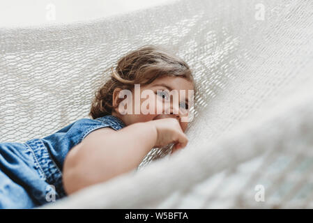 Young preschool aged girl resting in hammock looking away Stock Photo