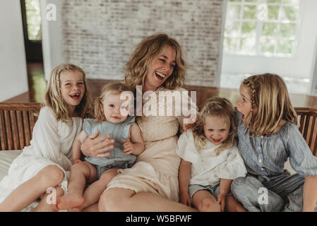 Mother and daughters laughing at each other on studio couch Stock Photo