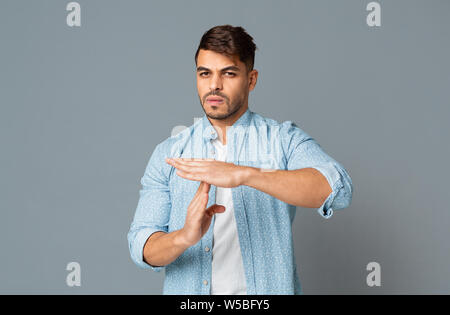 Man Making Time Out Gesture On Gray Background Stock Photo