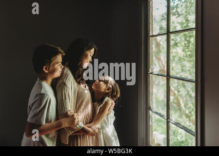 Mother, son, and daughter embrace and look at each other Stock Photo
