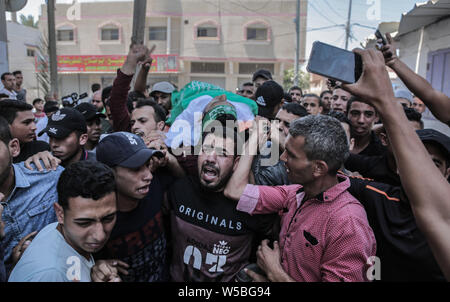 (EDITOR’S NOTE: Image depicts death)Palestinian mourners carry the body of Ahmed Mohammed, during the funeral procession. Palestinian, Ahmed Mohammed al-Qara, 23 received his last farewell in the southern Gaza Strip town of Khan Yunis, he was wounded by a live bullet in the abdomen during the 'Al-Awda al-Kobra' demonstration in Khan Younis on 26th Jul 2019. Stock Photo