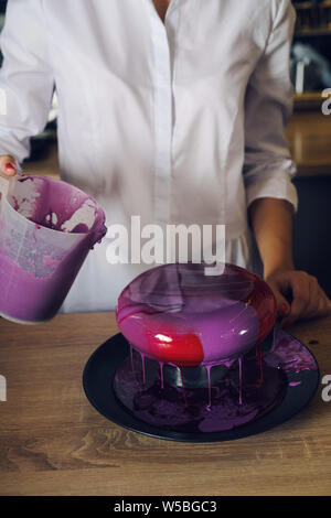 Young and beautiful women holding spatula and smoothing syrup on a cak Stock Photo