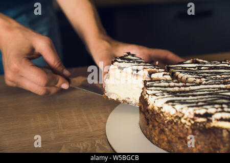 Women's hands hold the piece of cut cake on knife. Close up Stock Photo