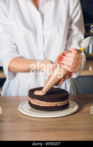 Young and beautiful woman in white shirt squeezes out chocolate cream Stock Photo