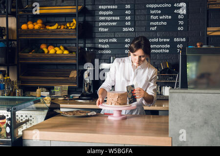 Woman's hands in white shirt  smoothing cream on a side  of chocolate Stock Photo