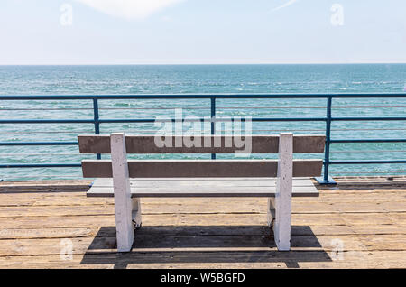 Empty bench with sea view on wooden deck, blue sky and sea background, Santa Monica pier, California Stock Photo