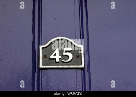 House number 45 with the forty five on a sign on a dark purple door Stock Photo
