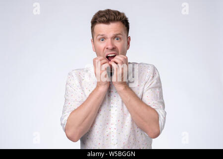 Young man covering mouth with hands and round eyes experiencing deep astonishment Stock Photo